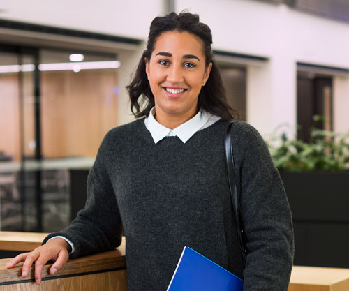 Happy student leaning on a high bench with document in one hand